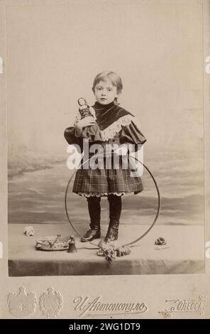 Portrait d'une fille avec un cerceau et une poupée, 1900. Cette collection contient 136 photographies d'Irkoutsk de la fin du XIXe siècle et du début du XXe siècle. Les photographies montrent des vues de la ville d'Irkoutsk et de la campagne de la province d'Irkoutsk ; les moyens de transport ; et les citoyens ; y compris leur mode de vie, les activités sociales et les formes de divertissement. Musée d'histoire municipale d'Irkoutsk Banque D'Images