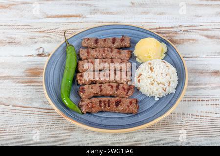Cuisine turque boulettes de viande inegol. Boulettes de viande grillées sur une assiette. Tekirdag turc ou inegol Kofte avec poivre, riz et purée de pommes de terre, Kofta. Banque D'Images