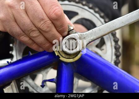 Gros plan de la main d'un homme occupé à réparer un vélo. Il serre le boulon de frein de vélo avec une clé à douille. Banque D'Images