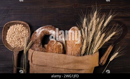 Dans le sac de jute différents types de pain, complet avec des graines et des céréales et quelques épis de maïs. Nature morte. vue de dessus. Banque D'Images