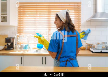 Femme de ménage comme elle nettoie diligemment et organise la cuisine à la maison une attention méticuleuse aux détails et le dévouement de l'équipe de nettoyage Banque D'Images