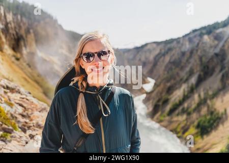 Jeune femme souriante au sommet du Grand Canyon de la rivière Yellowstone, dans le parc national de Yellowstone Banque D'Images