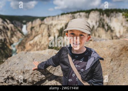 Jeune garçon souriant devant Lower Falls dans le parc national de Yellowstone Banque D'Images