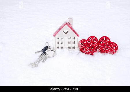 Clés de la petite maison et deux coeurs dans la neige - Saint Valentin, l'amour dans la maison. Logement de couple, immobilier, loyer, hypothèque, relocalisation. Confort et chaleur Banque D'Images