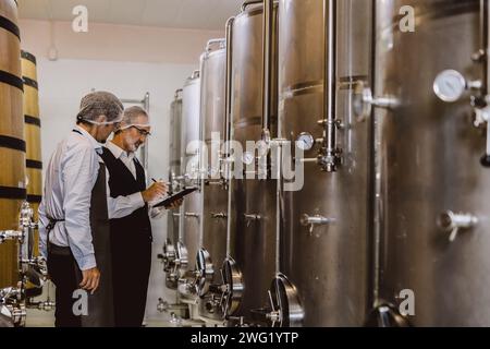 Viticulteur professionnel travaillant dans une grande usine de vinification moderne alcool alcool alcool industrie du contrôle de la qualité et de la fermentation surveillent la couleur vintage à Banque D'Images