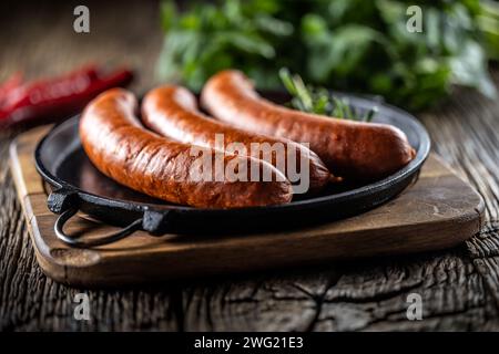 Saucisses fumées de porc au poivre avec du romarin dans une poêle en fonte. Banque D'Images