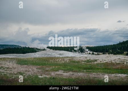 Vapeur s'élevant du geyser Old Faithful sous un ciel couvert au crépuscule dans le parc national de Yellowstone Banque D'Images