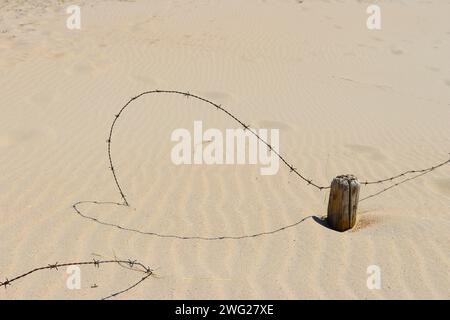 Barbelés enterrés dans le sable sur la plage Banque D'Images