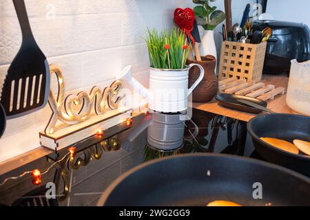 L'intérieur de la cuisine de la maison est décoré de coeurs rouges pour la Saint-Valentin. Décoration sur la table, cuisinière, ustensiles, ambiance festive dans un fari Banque D'Images