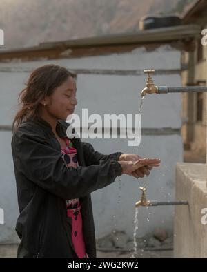 Une jeune népalaise se lave les mains avec de l'eau provenant d'une source d'eau d'un village à Palata, district de Dolpa, Népal occidental, 2023. Banque D'Images