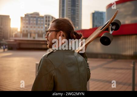 Portrait pleine longueur de skateboarder hipster Guy sur fond urbain Banque D'Images