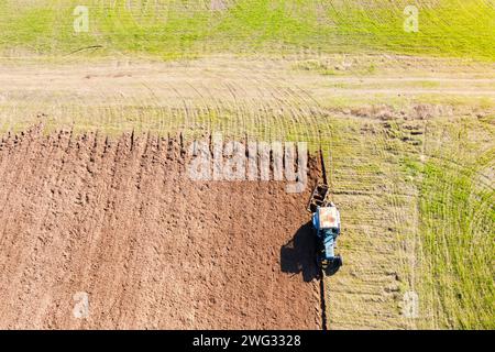 Vue aérienne de dessus du sol de labourage du tracteur sur un champ agricole. Concept d'entreprise agricole. Préparation du sol pour la nouvelle culture. Banque D'Images