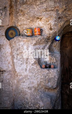 décoration dans la porte d'une porte d'une maison sculptée dans la roche en cappadoce, turquie, quelques tasses, une assiette et un service à thé avec une amulette turque typique Banque D'Images