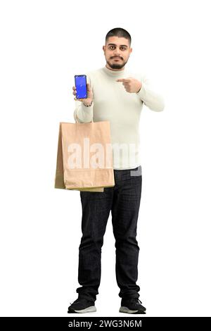 Un homme, pleine longueur, sur fond blanc, avec des sacs, montre un téléphone Banque D'Images