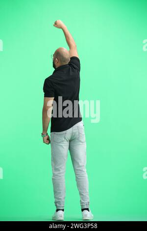 Un homme, sur fond vert, en pleine hauteur, leva la main Banque D'Images