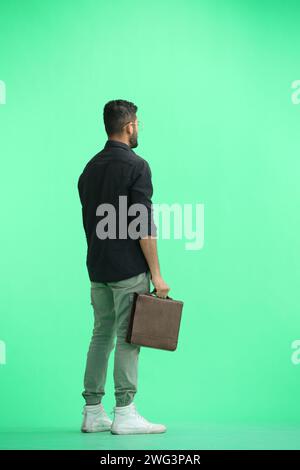 Un homme, sur fond vert, en pleine hauteur, avec une mallette Banque D'Images