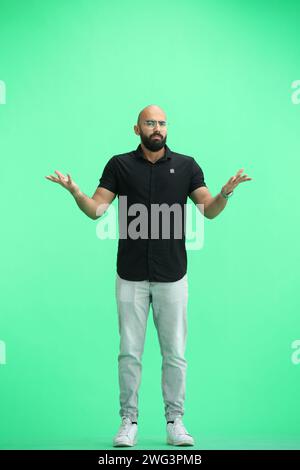 Un homme, sur fond vert, en pleine hauteur, déploie les bras Banque D'Images