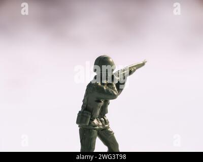 Un soldat jouet de guerre capturé en gros plan, illuminé par la lumière du jour sur un champ de bataille froid et blanc enneigé. Banque D'Images