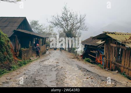 Paysage de rêve d'une route boueuse et maison natale sur un jour d'hiver brumeux, vie quotidienne authentique dans le village indigène Lao Chai à sa PA Vietnam Banque D'Images
