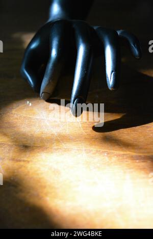 Statuette noire d'une main féminine mate sur un bois brun avec un rayon ensoleillé Banque D'Images