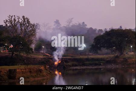 Bûchers de crémation funéraire hindous traditionnels brûlant à Jagaddal Ghat sur les rives de la rivière Hooghly au crépuscule dans le North Barrackpore, Bengale occidental, Inde Banque D'Images