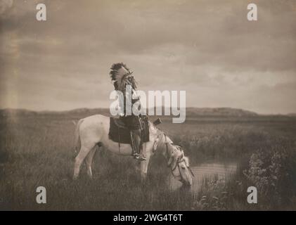 Une oasis dans les Badlands, c1905. La photographie montre Red Hawk, un guerrier Oglala, assis sur un cheval qui boit dans un petit étang dans les Badlands du Dakota du Nord. Banque D'Images