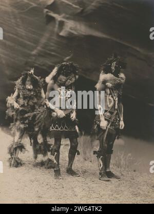 Dieux de guerre Yeibichai, 1904, c1905. La photographie montre trois natifs : Tonenili, Tobadzischini et Nayenezgani, en robe de cérémonie, photographiés sur fond rocheux sombre. Banque D'Images