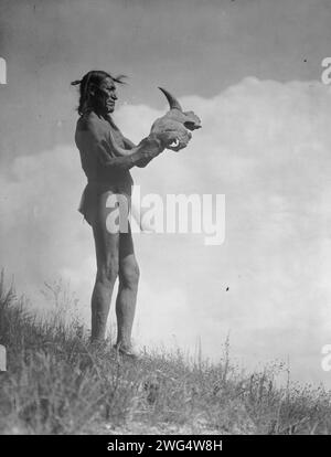 Goupille de piquet, c1907. Portrait en pied d'un homme Dakota vêtu d'une longe tenant le crâne de buffle. Banque D'Images