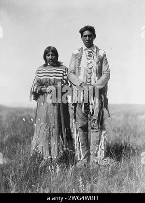 Joe Russell, c1910. Piegan homme et femme debout dans la prairie ouverte. Banque D'Images