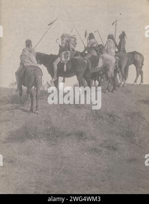 Surplombant la petite corne, 1908. La photographie montre cinq Indiens Crow, Wolf, Fish shows (portant une coiffe), What Way, Lone Tree, et deux sifflets sur le cheval portant des staff. Banque D'Images