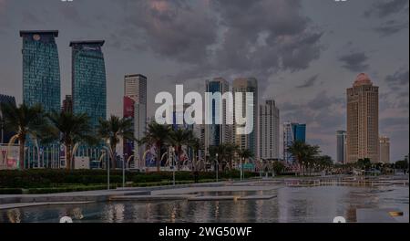 Horizon de Doha dans la baie ouest Doha, Qatar prise de vue de l'après-midi depuis le parc de l'hôtel avec lac artificiel au premier plan et nuages dans le ciel en arrière-plan Banque D'Images
