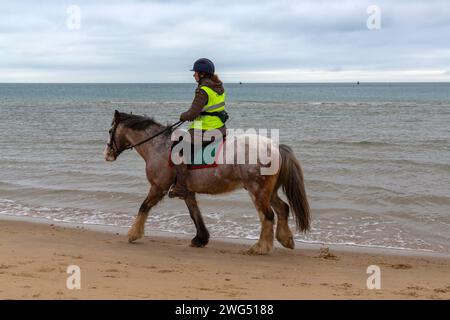 Studland, Dorset Royaume-Uni. 3 février 2023. Météo britannique : nuageux, mais doux à la plage de Studland alors que les visiteurs se dirigent vers le bord de mer pour un peu d'air frais et d'exercice. Cavalier profite d'une balade le long du bord de mer. Crédit : Carolyn Jenkins/Alamy Live News Banque D'Images