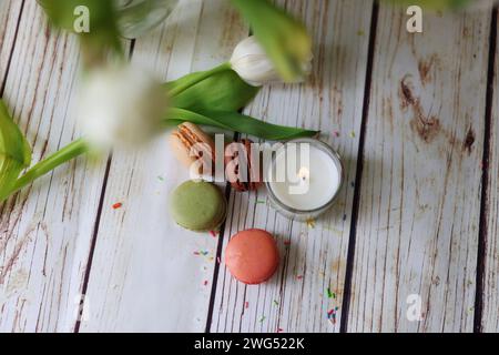Nature morte romantique avec une bougie, des macarons et des tulipes Banque D'Images