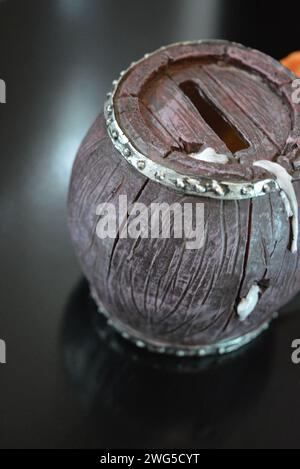 Statuette en céramique, une tirelire pour l'argent sous la forme d'un chien regardant hors d'une cabine en forme de tonneau avec de la bière sous la surface noire brillante. Banque D'Images