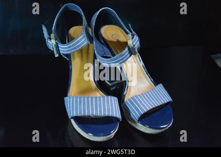 Chaussures femme élégantes et inhabituelles en cuir verni bleu véritable et tissu bleu. Sandales, sandales, chaussures de vol sont situés sur un noir brillant. Banque D'Images