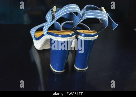 Chaussures femme élégantes et inhabituelles en cuir verni bleu véritable et tissu bleu. Sandales, sandales, chaussures de vol sont situés sur un noir brillant. Banque D'Images