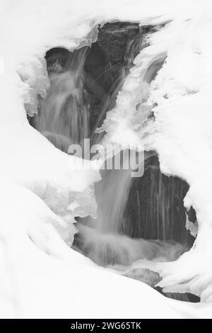 Deux trous dans la glace et la neige révèlent une cascade dans le parc de la Gatineau, au Québec. Banque D'Images