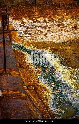 Les teintes orange vibrantes d'un ruisseau acide contrastent avec un mur de pierre dans la zone minière historique de Rio Tinto Banque D'Images