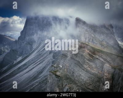 Seceda dans les Dolomites, en Italie, avec des crêtes rocheuses spectaculaires, de la brume et des pics alpins couverts de nuages créant un paysage montagneux sombre dans le Tyrol du Sud Banque D'Images