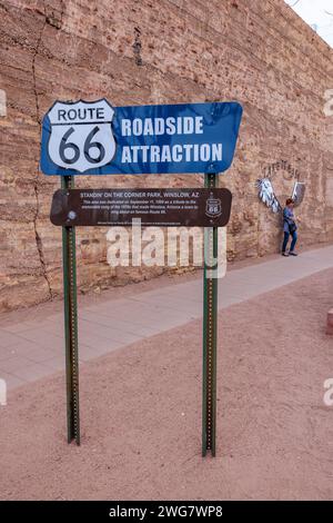 Femme posant pour une photo derrière le panneau d'attraction au bord de la route à Standin' on the Corner Park dans le centre-ville de Winslow, Arizona Banque D'Images