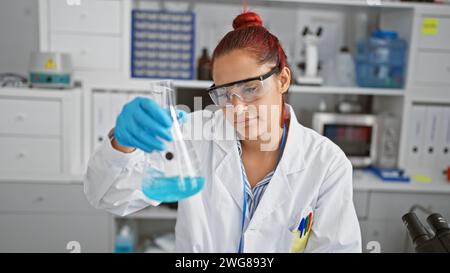Brillante jeune femme rousse scientifique engrosée dans la recherche médicale, mesurant méticuleusement le liquide dans un tube à essai, gants de sécurité sur, à la h occupé Banque D'Images
