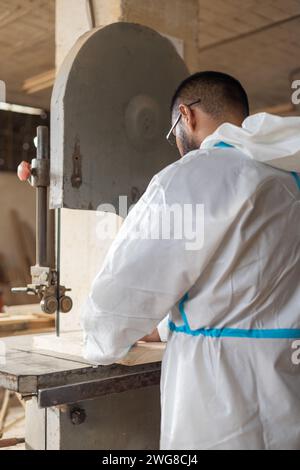 homme travaillant sur la scie à bois, intérieur de menuiserie avec des machines industrielles, travail et occupation artisanale, équipement moderne Banque D'Images