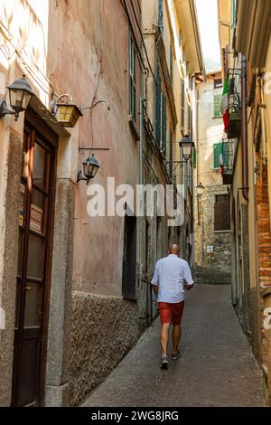 Un homme marche vers le haut dans un passage étroit entre les bâtiments de Bellano, Lombardie, Italie. Banque D'Images