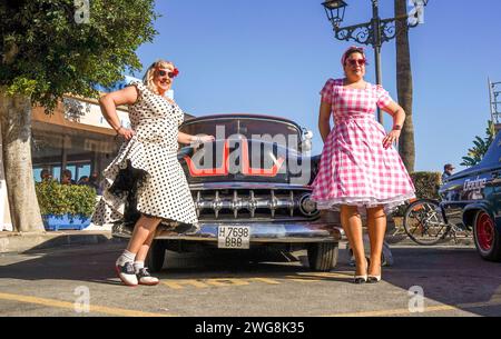 Deux femmes habillées dans le style des années cinquante posant devant une vieille voiture classique au Rockin Race Jamboree festival 2024, rockabillies, Torremolinos, Espagne. Banque D'Images