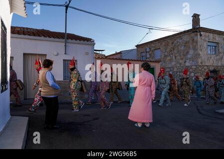 Almonacid de Marquesado, Cuenca, Espagne. 3 février 2024. Les membres de la confrérie Endiablada défilent pendant que deux femmes les regardent pendant le festival traditionnel 'Endiablada' à Almonacid Del Marquesado, Espagne. Chaque année, du 2 au 3 février, la ville d'Almonacid del Marquesado dans le centre de l'Espagne accueille le vibrant festival ''Endiablada'' (la Fraternité des Diables). une tradition datant de l'époque médiévale ou plus tôt en l'honneur de la Candelaria et San Blas. Au cours de cet événement animé, les participants masculins arborent une tenue diabolique, notamment des costumes de combinaison éclatants et des chapeaux d'onglet rouges. Crédit : ZUMA Press, Inc. Banque D'Images