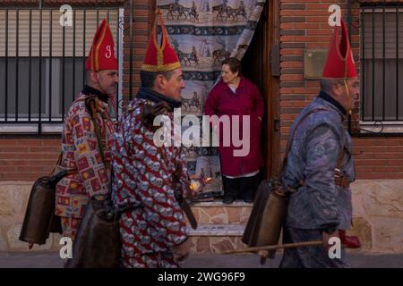 Almonacid de Marquesado, Cuenca, Espagne. 3 février 2024. Une femme regarde de chez elle comme des membres de la confrérie Endiablada défilent pendant le festival traditionnel 'Endiablada' à Almonacid Del Marquesado, Espagne. Chaque année, du 2 au 3 février, la ville d'Almonacid del Marquesado dans le centre de l'Espagne accueille le vibrant festival ''Endiablada'' (la confrérie des Diables). une tradition datant de l'époque médiévale ou plus tôt en l'honneur de la Candelaria et San Blas. Au cours de cet événement animé, les participants masculins arborent une tenue diabolique, notamment des costumes de combinaison éclatants et des chapeaux d'onglet rouges. Crédit : ZUMA Pre Banque D'Images