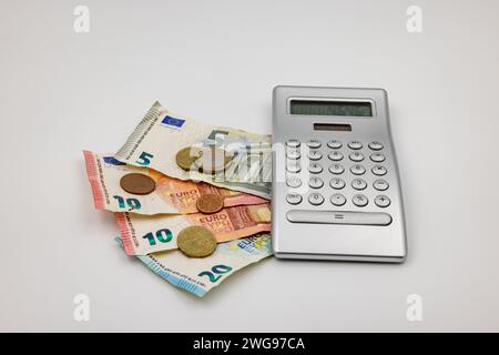 Dans une crise avec une inflation élevée et des prix en hausse, vous tournez chaque centime deux fois et calculez les coûts et le salaire avec une calculatrice Banque D'Images