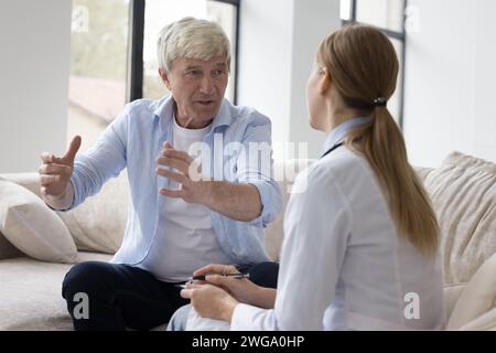 Ancien retraité parlant à une femme médecin à la maison Banque D'Images