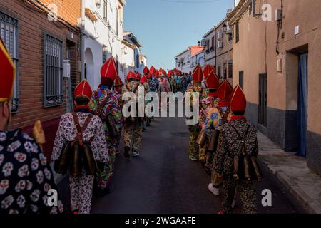 Les membres de la confrérie Endiablada défilent pendant la fête traditionnelle Endiablada. Chaque année, du 2 au 3 février, la ville d'Almonacid del Marquesado dans le centre de l'Espagne accueille les festivités animées 'Endiablada' (la Fraternité des Diables), une tradition datant de l'époque médiévale ou plus tôt en l'honneur de la Candelaria et San Blas. Au cours de cet événement animé, les participants masculins arborent une tenue diabolique, notamment des costumes de combinaison éclatants et des chapeaux d'onglet rouges. Ornés de cloches de cuivre de taille importante autour de leur taille, les festivités se déroulent alors qu'ils traversent les rues sinueuses de la ville, s'engageant dans dan Banque D'Images