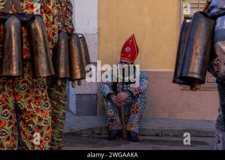 Un membre de la confrérie 'Endiablada' attend la procession de la sainte pendant la fête traditionnelle 'Endiablada'. Chaque année, du 2 au 3 février, la ville d'Almonacid del Marquesado dans le centre de l'Espagne accueille les festivités animées 'Endiablada' (la Fraternité des Diables), une tradition datant de l'époque médiévale ou plus tôt en l'honneur de la Candelaria et San Blas. Au cours de cet événement animé, les participants masculins arborent une tenue diabolique, notamment des costumes de combinaison éclatants et des chapeaux d'onglet rouges. Ornés de cloches en cuivre de taille importante autour de leur taille, les festivités se déroulent à mesure qu'ils traversent le méandre de la ville Banque D'Images